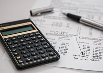 Calculadora financeira e uma caneta sobre um papel com contas